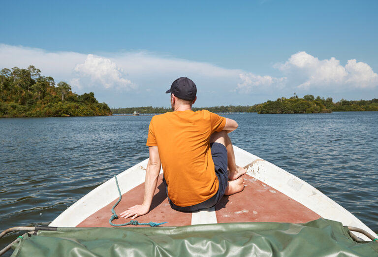 Rear,View,Of,Man,Sitting,On,Bow,Of,Boat,During